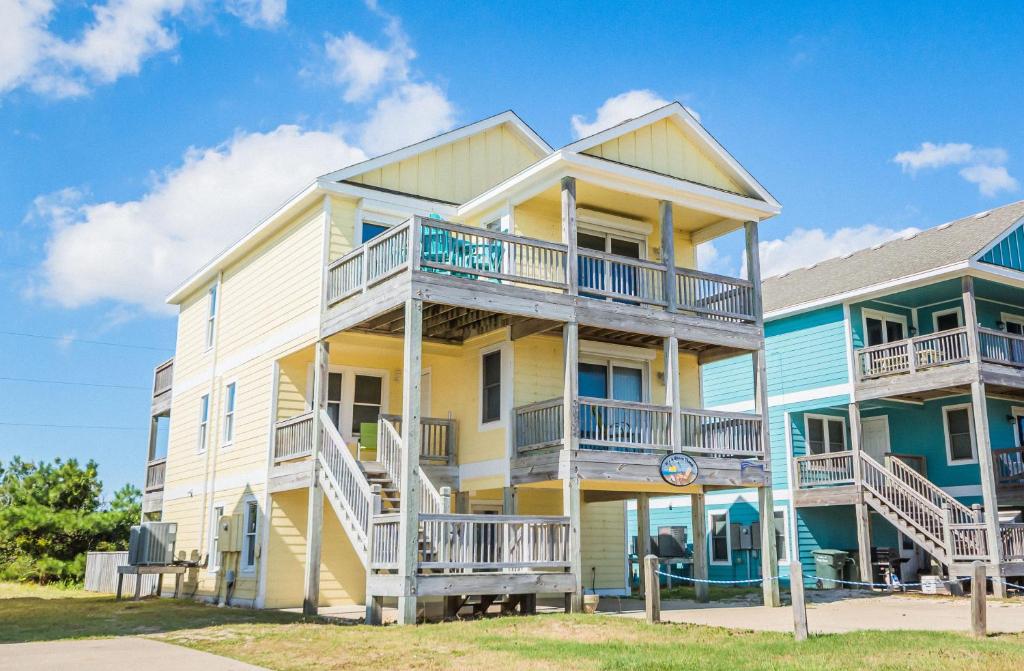 a large yellow and blue house with balconies at It's A Shore Thing - Nags Head MP 11.5, Ocean View, 130 Yds to Beach, Pool, Hot Tub, Rec Room in Nags Head