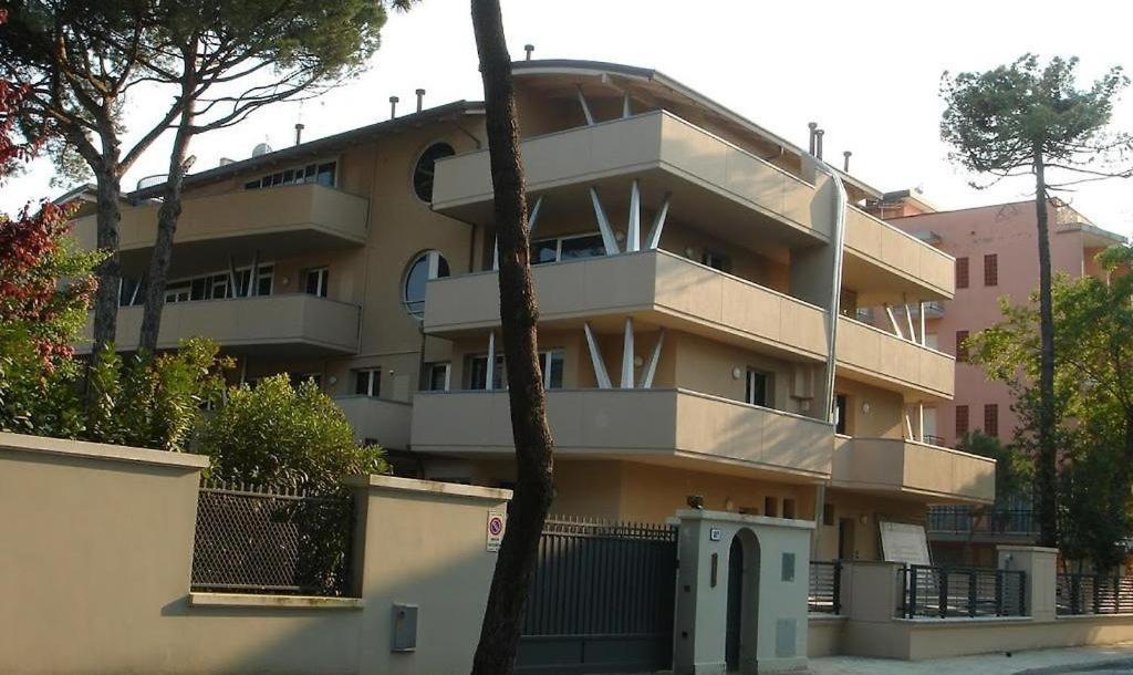 ein großes Gebäude mit einem Baum davor in der Unterkunft Residence La Settima in Milano Marittima
