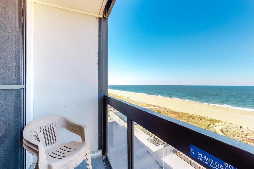 a white chair sitting on a balcony overlooking the beach at Golden Sands 714 in Ocean City