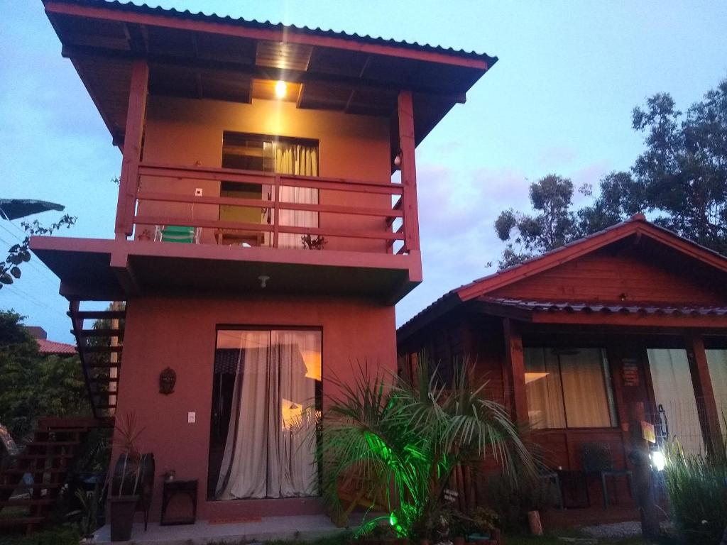 una casa roja con balcón en la parte superior. en Praia do Rosa loft com cozinha, en Imbituba
