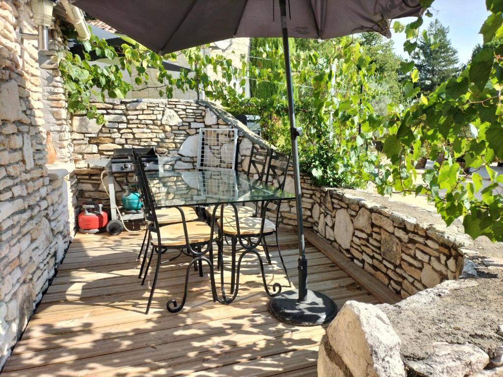 a table and chairs with an umbrella on a patio at Apartments La Vieille Source in Saint-Martin-dʼArdèche