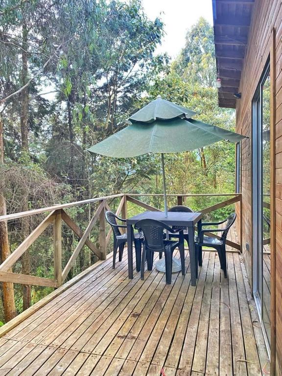 a table and chairs on a deck with an umbrella at Encantador Glamping Alaska in Medellín