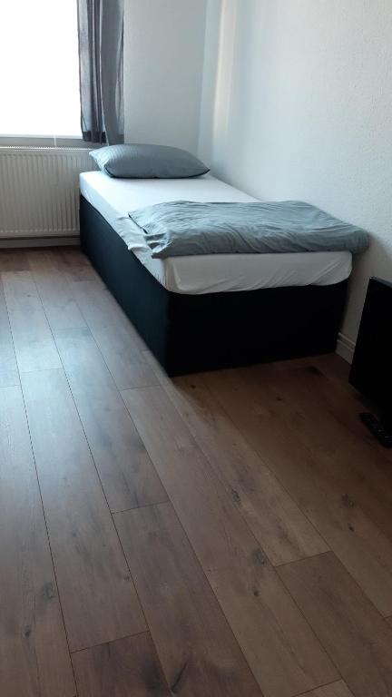 Bett in einem Zimmer mit Holzboden in der Unterkunft Apart Burg in Burg bei Magdeburg