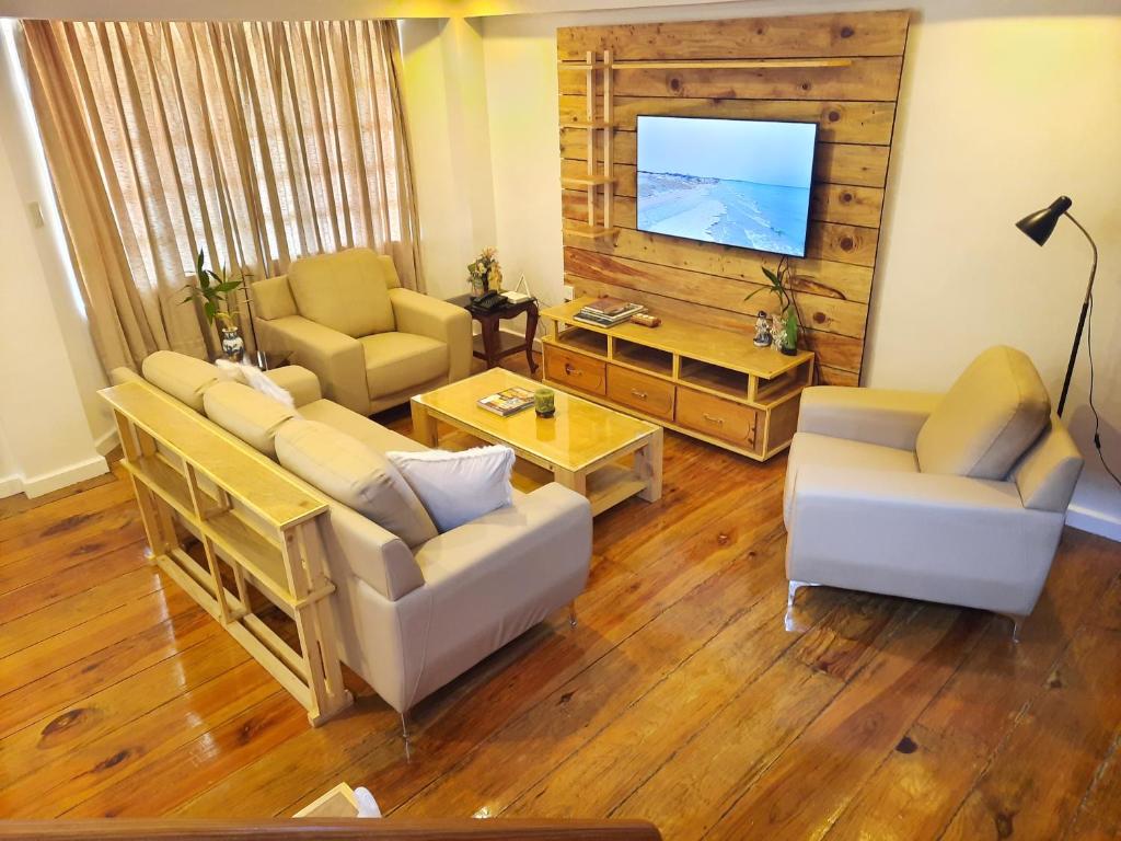 sala de estar con sofás y TV de pantalla plana. en The White Pine at No 7 Pucay Village en Baguio