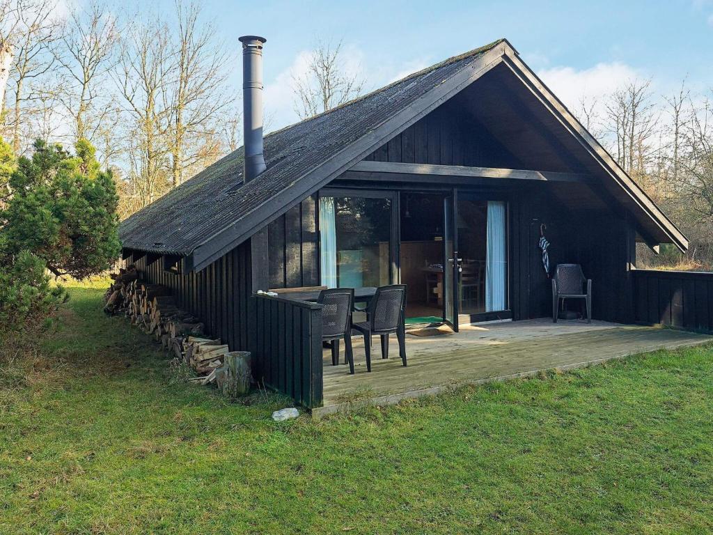 ein kleines schwarzes Haus mit einer Veranda und einer Terrasse in der Unterkunft 4 person holiday home in Martofte in Martofte