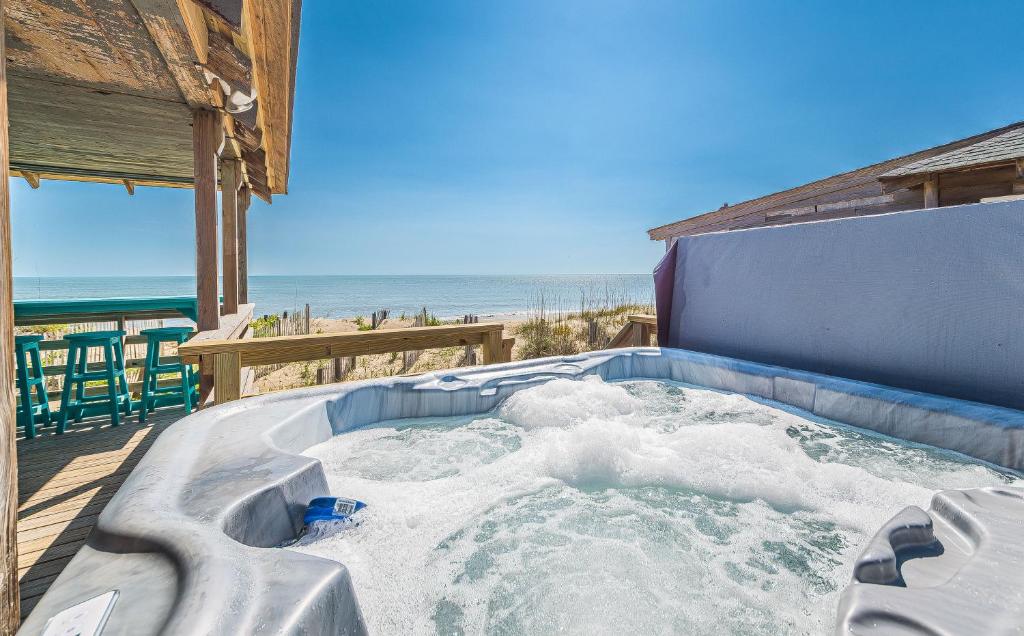 un jacuzzi sur une terrasse avec la plage dans l'établissement Deja Blue, à Kill Devil Hills