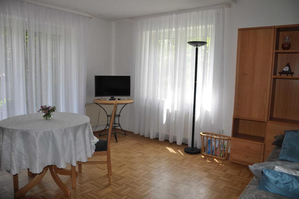 a living room with a table and a tv and curtains at Ferienwohnung Fischer in Meersburg
