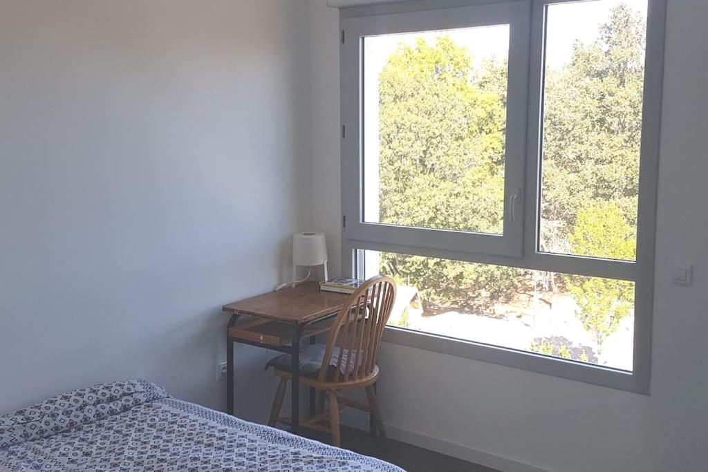 a bedroom with a desk and a bed and two windows at Appartement entier in Rennes