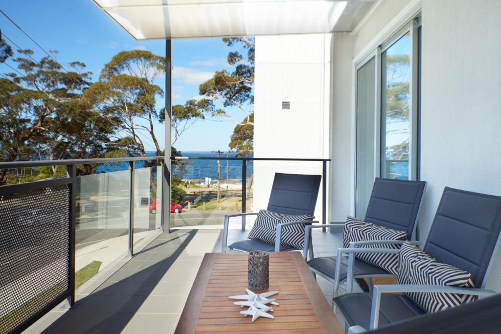 a balcony with a table and chairs and a view of the ocean at Tranquility the Beach in Huskisson