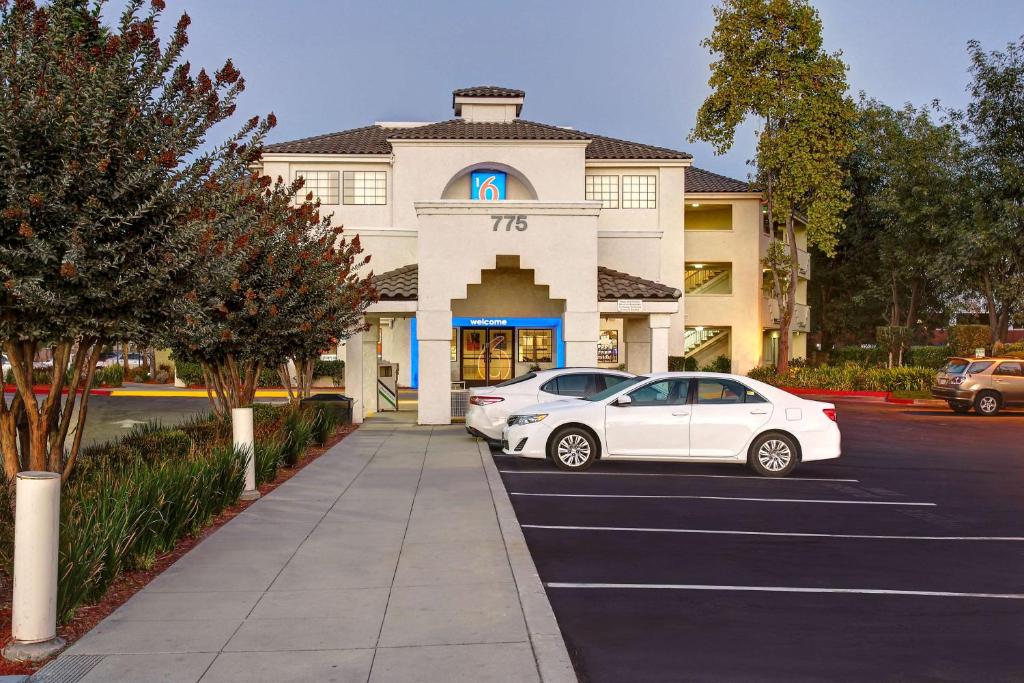 un coche blanco estacionado en un estacionamiento frente a un edificio en Motel 6-Sunnyvale, CA - North, en Sunnyvale