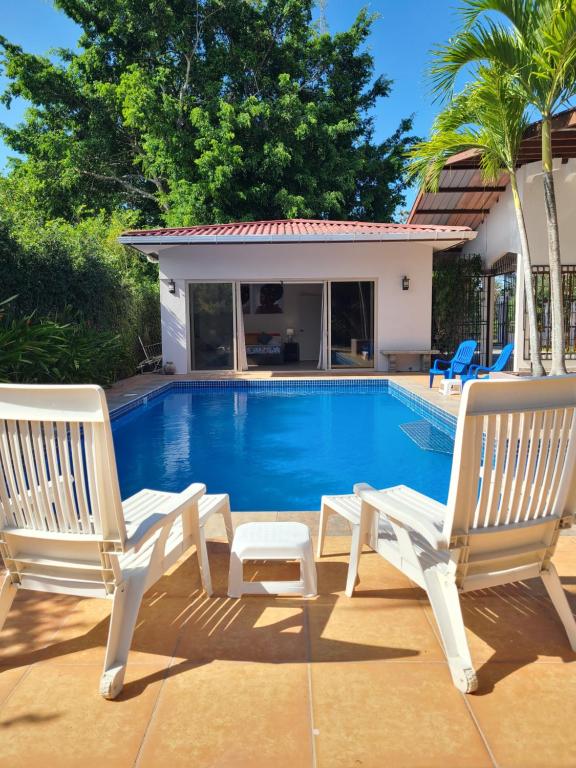 two white chairs sitting next to a swimming pool at Pool House with Shared Pool Access in David