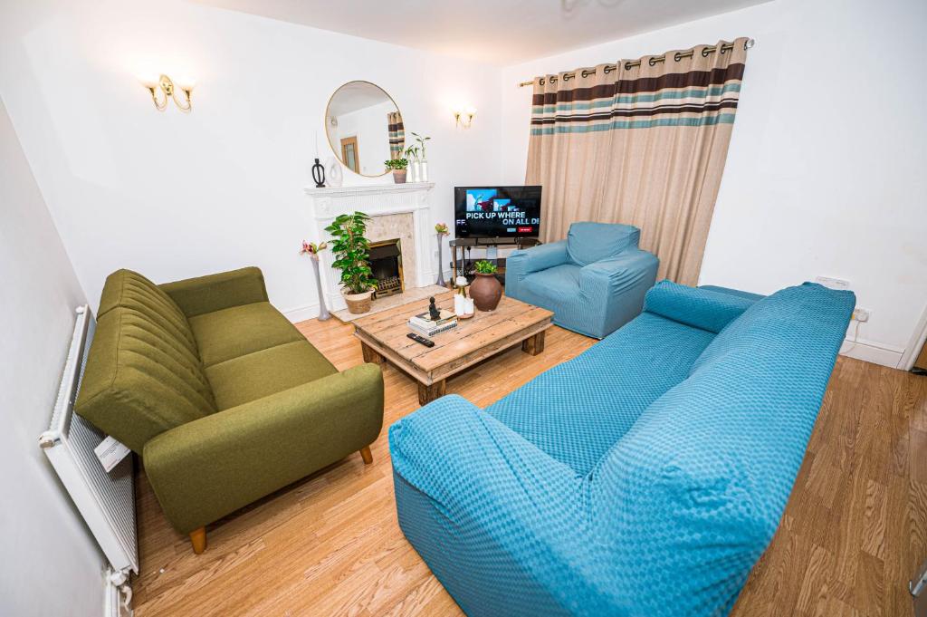 uma sala de estar com um sofá azul e duas cadeiras em #Gorgeous 3 beds home#7min to subway, free parking em Thamesmead