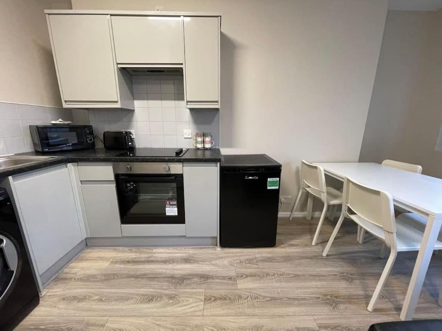 una cocina con armarios blancos y una mesa con sillas. en Hosted By Ryan - 1 Bedroom Apartment, en Liverpool