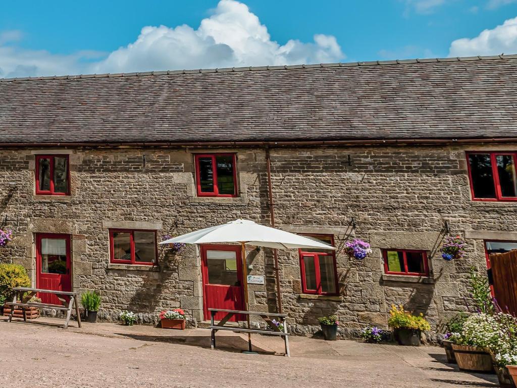 un edificio de piedra con una sombrilla delante de él en Pine Cottage - Rchp140 en Calton