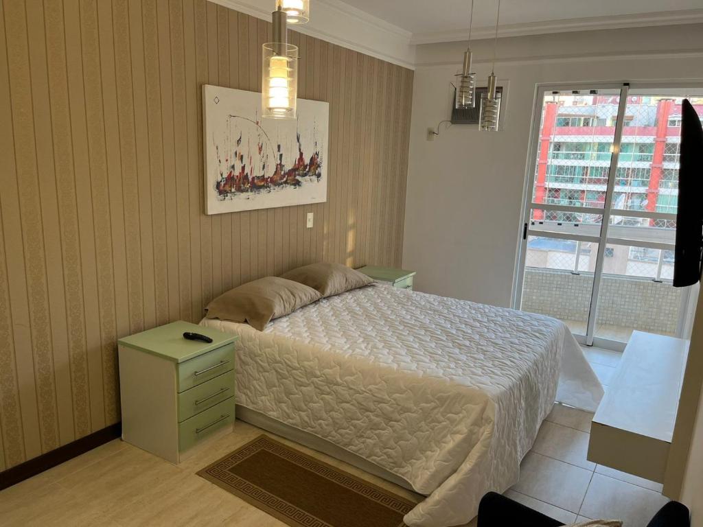 Un dormitorio con una cama grande y una ventana en Apartamento Itapema SC 70m do mar, en Itapema