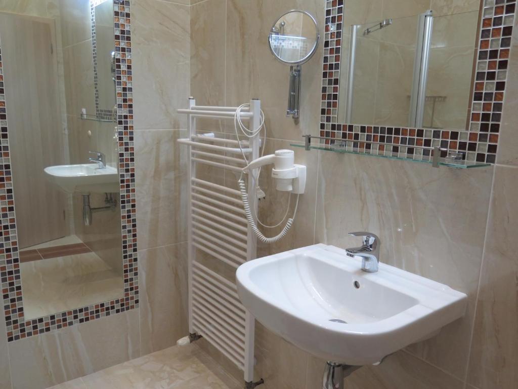 a bathroom with a sink and a shower and a mirror at Penzion Fryštátská Chalupa in Karviná