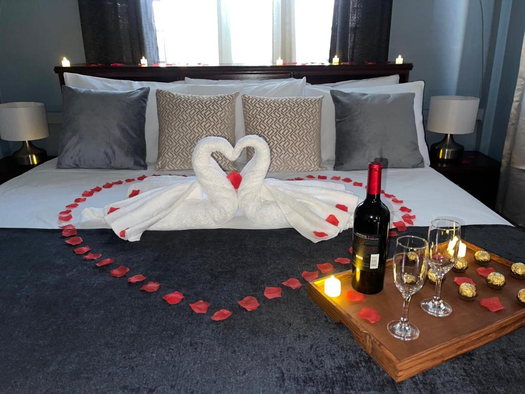 Una cama con dos cisnes haciendo un corazón con una botella de vino en The Colosseum en Basseterre