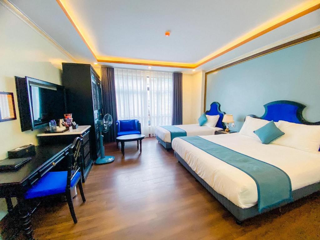 a hotel room with two beds and a desk at Aurora Hotel SaPa in Sapa