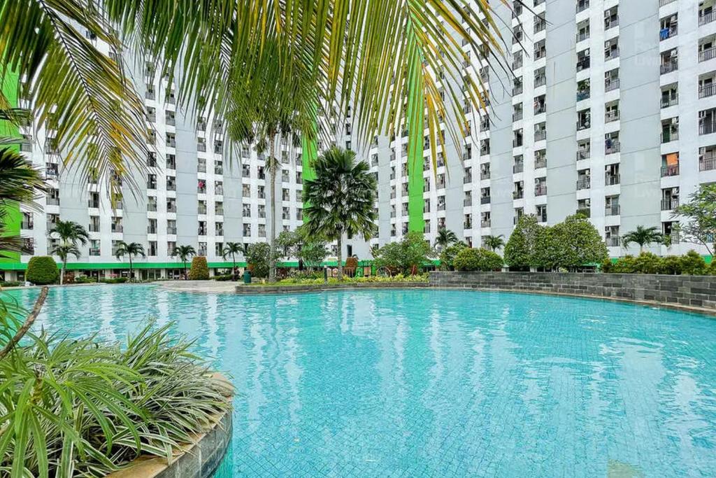 una grande piscina di fronte a un grande edificio di RedLiving Apartemen Green Lake View Ciputat - Hanna Property Tower B a Pondokcabe Hilir