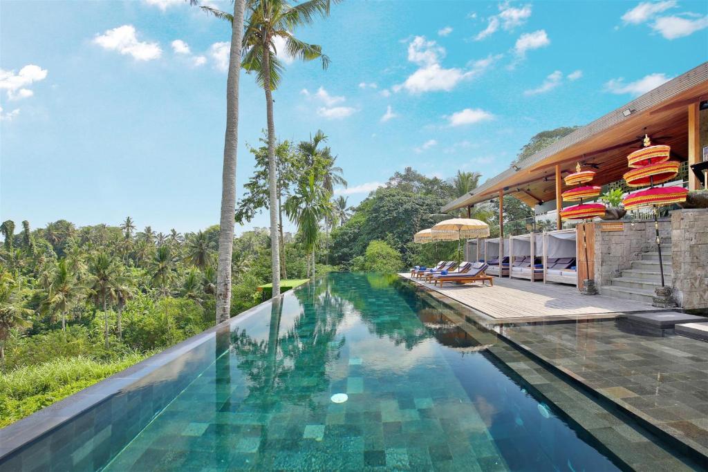 een overloopzwembad in een resort met palmbomen bij Kaamala Resort Ubud by Ini Vie Hospitality in Ubud