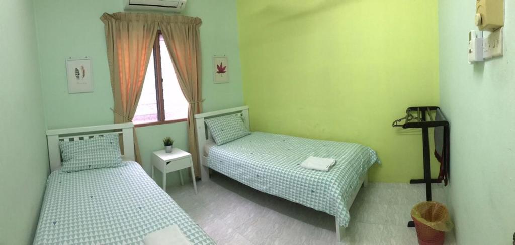 two beds in a small room with a window at Ruhani Homestay 2 Kota Bharu Cheap and Comfortable in Kota Bharu