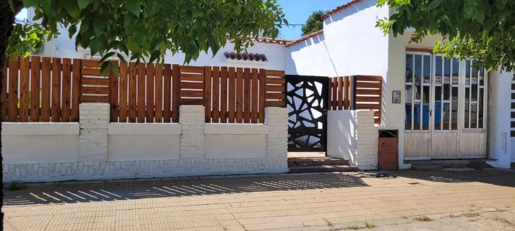 Casa blanca con puerta de madera y valla en RAMALLO CASA CENTRICA en Ramallo