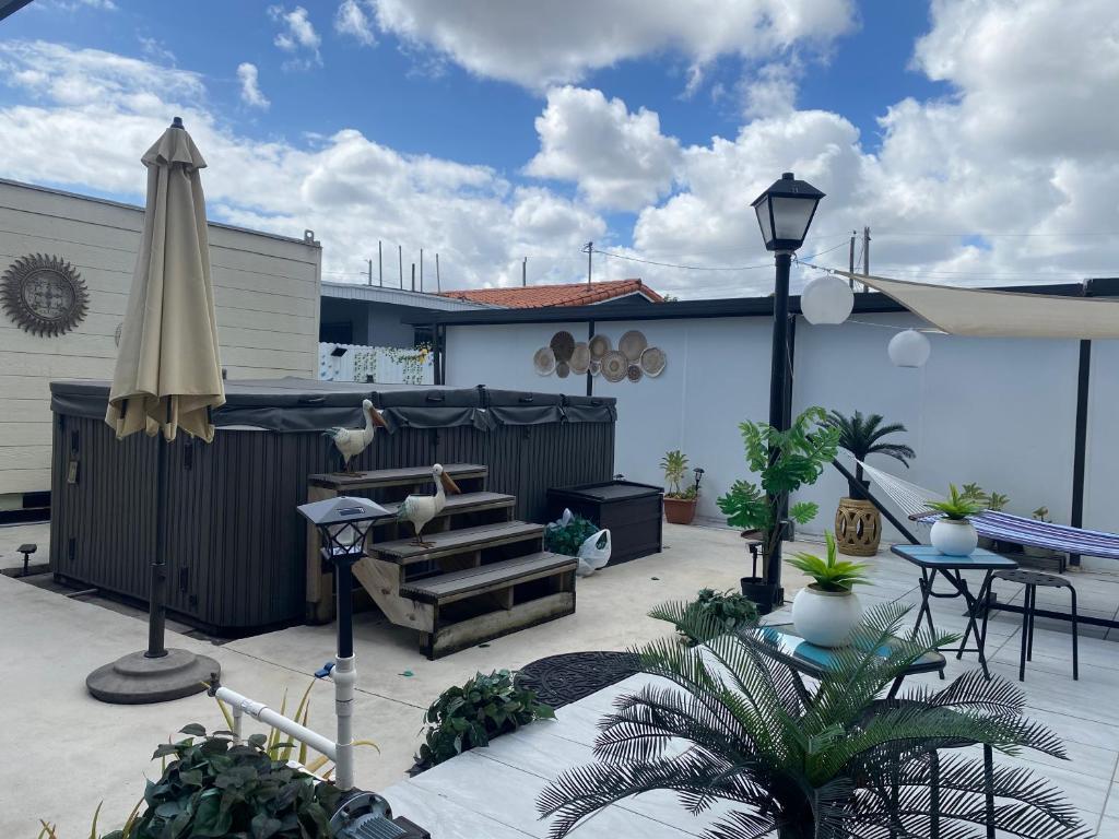 a patio with an umbrella and a bench and a table at Tiny place w private hot jacuzzi 7 min to Miami international airport in Miami