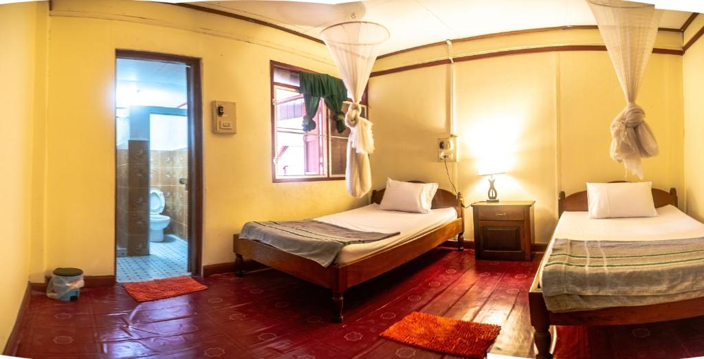 a room with two beds in a room with a mirror at Xaymountry Don Khon City Center Residence and Guesthouse in Ban Donsôm