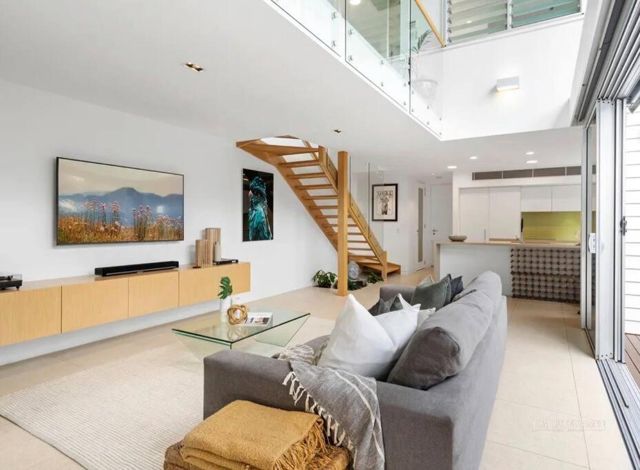 a living room with a gray couch and a staircase at Sunshine Beach Gem in Sunshine Beach