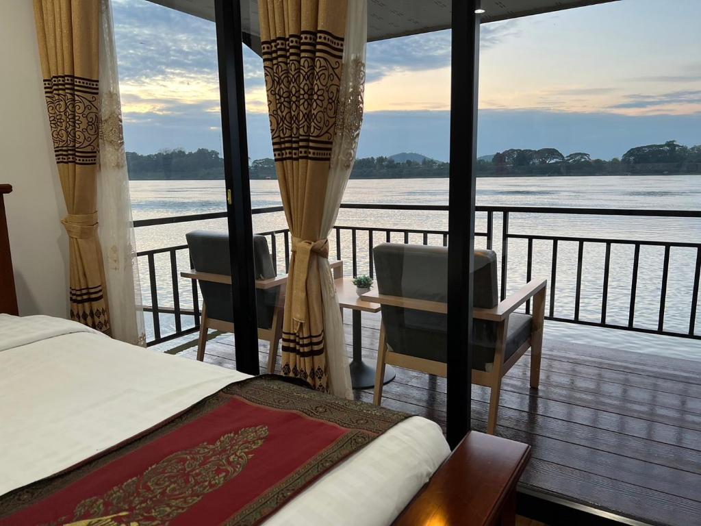 Schlafzimmer mit Balkon und Blick auf das Wasser in der Unterkunft Riverside Chiangkhan in Ban Mai Ta Saeng