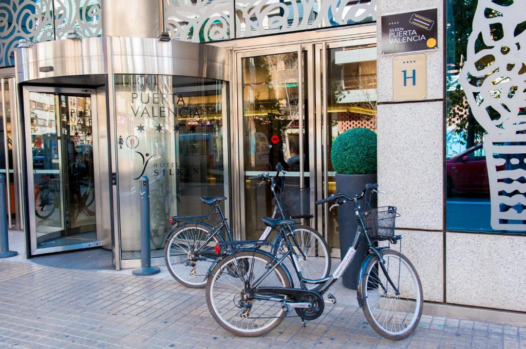 dos bicicletas están estacionadas frente a una tienda en Silken Puerta Valencia en Valencia