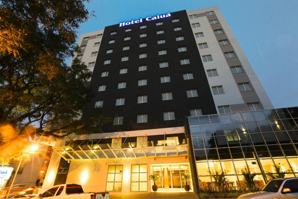 un edificio de hotel con coches estacionados frente a él en Hotel Caiuá Cascavel, en Cascavel