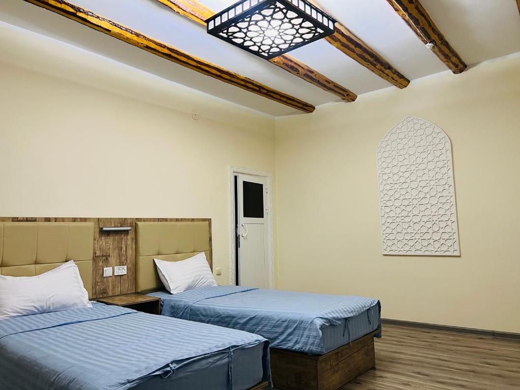 Habitación con 2 camas y ventana en la pared. en BUKHARA HOUSE hotel, en Bukhara