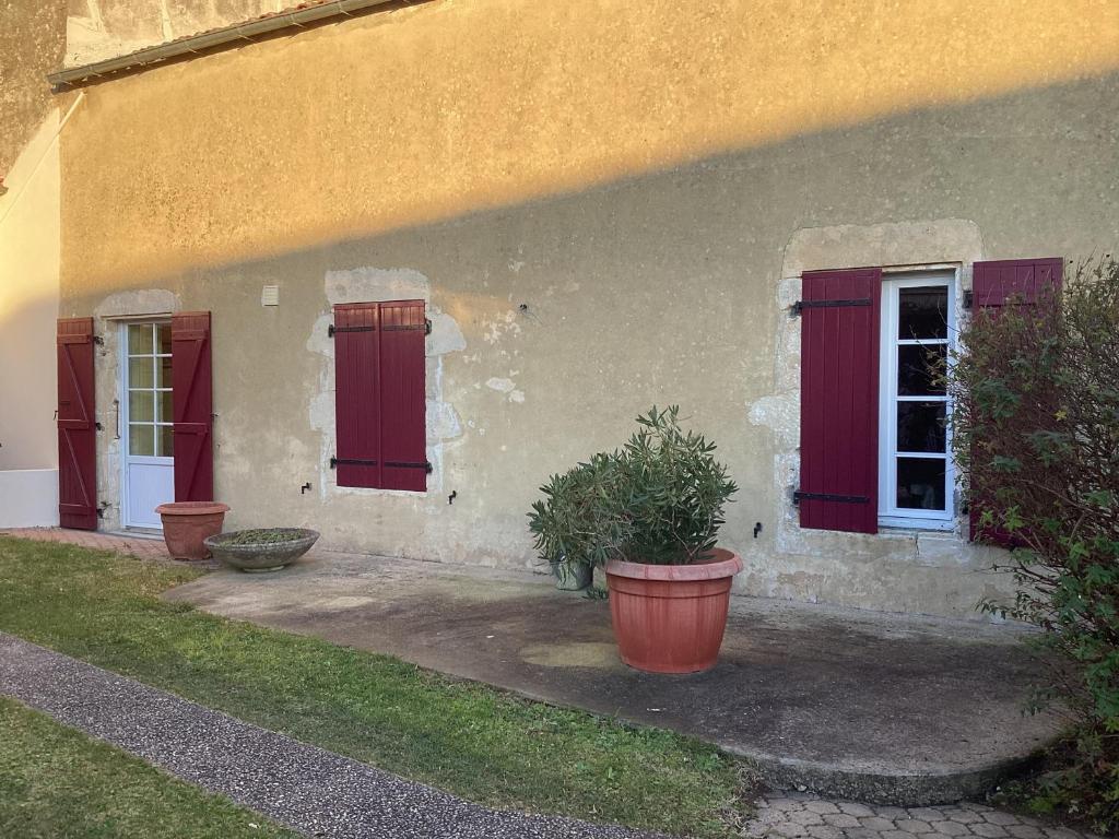 una casa con puertas rojas y una planta delante de ella en Maison 4 pers proche chatelaillon plage, 