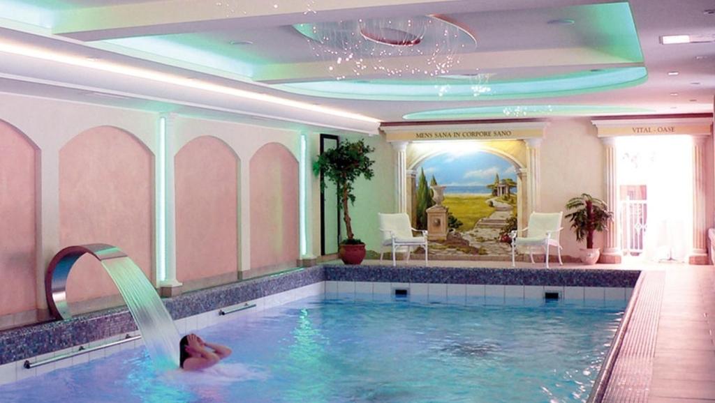 a pool in a hotel with a person in the water at Rüters Parkhotel in Willingen