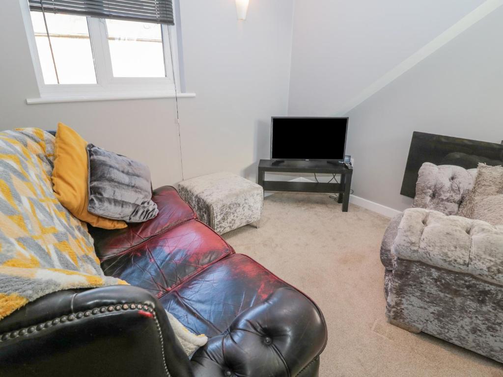 a living room with a leather couch and a television at The Apartment in Longframlington