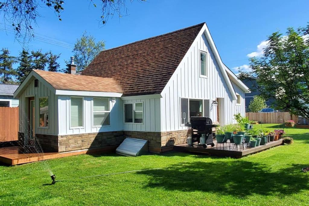 a small white house with a deck in a yard at Luxury DT Cottage - Free Parking - Self Check-In in Anchorage