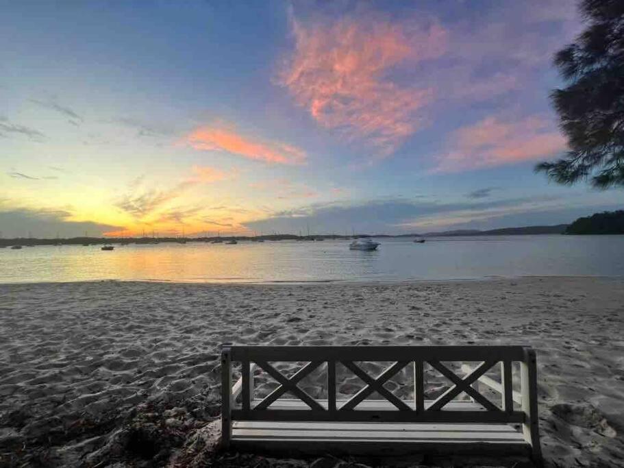 a bench sitting on a beach with a sunset at HighTide- luxury apartment, almost on the beach. in Corlette