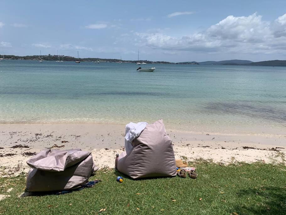 two bags on the beach with a boat in the water at HighTide- luxury apartment, almost on the beach. in Corlette