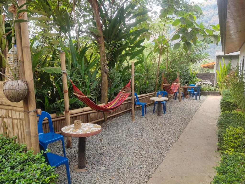 um grupo de cadeiras e redes de descanso num jardim em Meexok guesthouse em Nongkhiaw