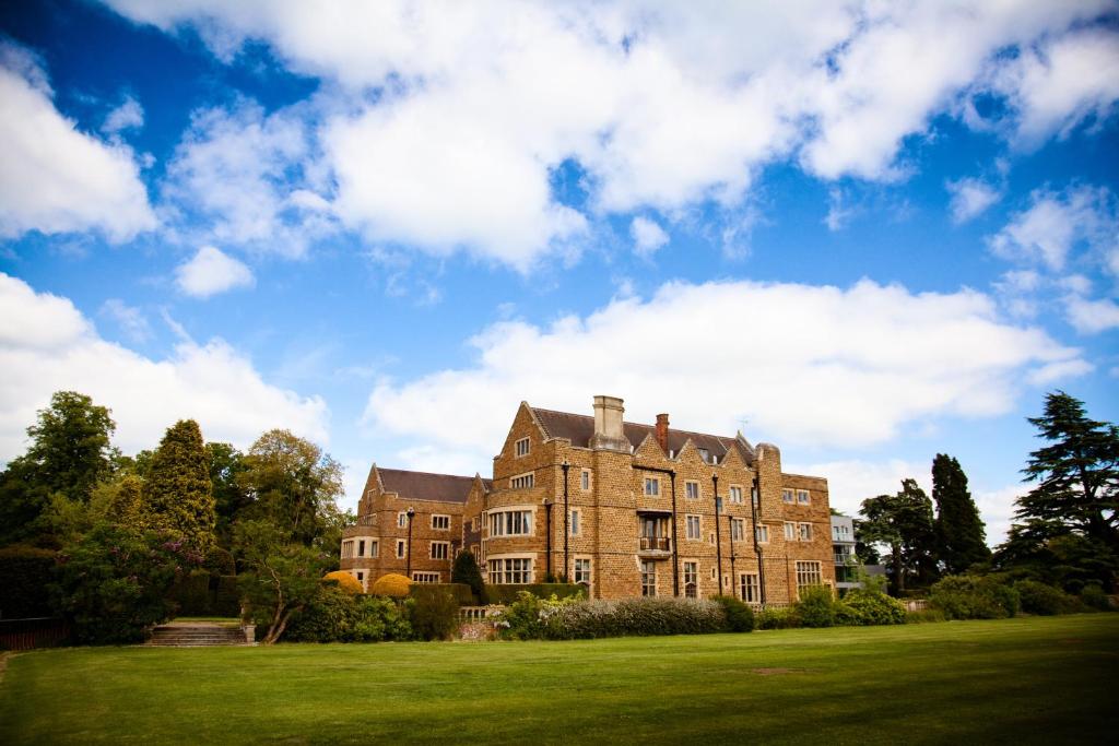 a large brick building on a lush green field at Ashorne Hill Leamington Spa in Leamington Spa