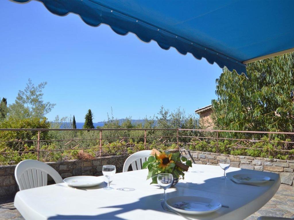 une table blanche avec des chaises blanches et un parapluie bleu dans l'établissement Villa californienne 4 chambres, terrasse vue mer, parking, animaux admis - FR-1-251-310, au Lavandou