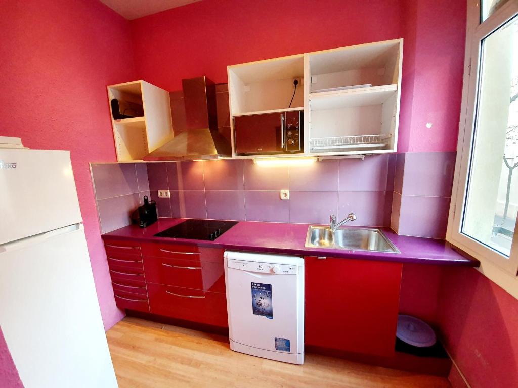 a red kitchen with a sink and a dishwasher at Apartamento Llibertat centro in Vilanova i la Geltrú