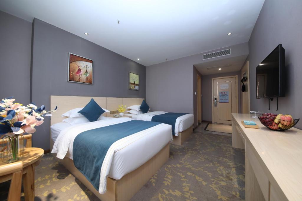 a hotel room with two beds and a television at Jin Hui Business Hotel in Guangzhou