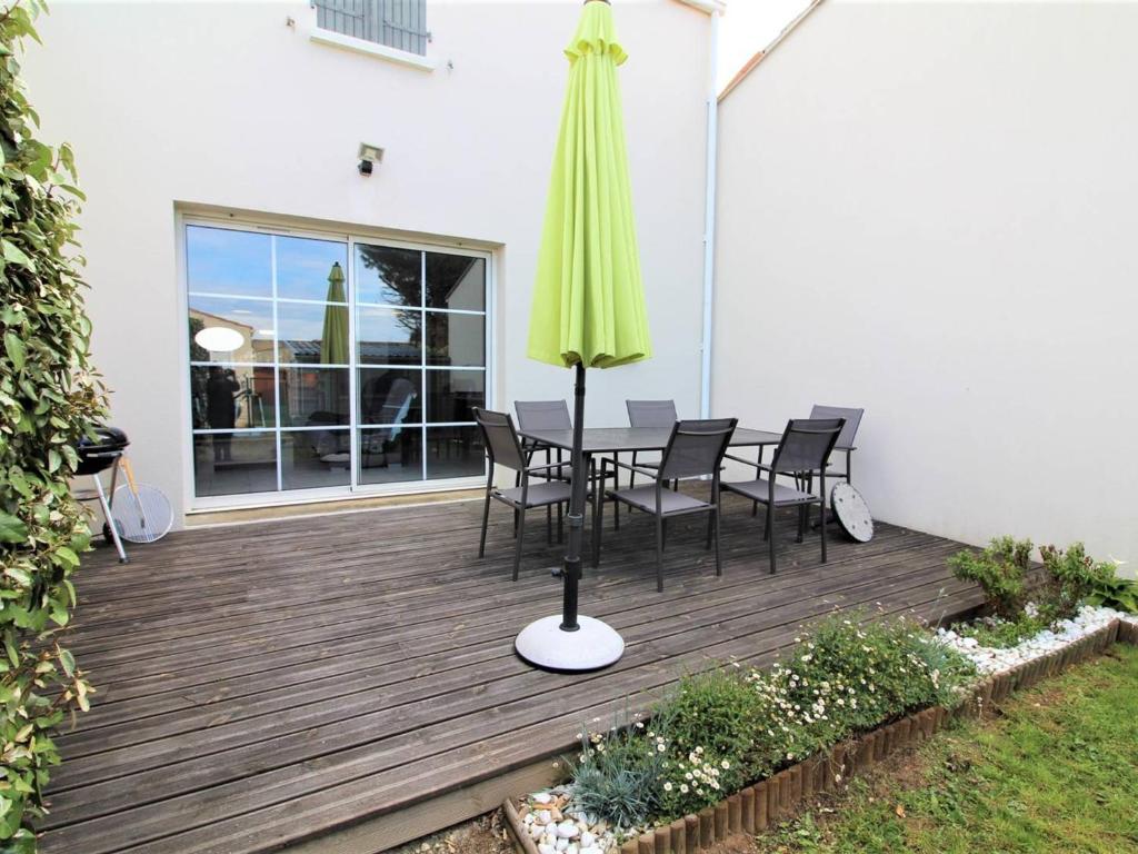 un patio avec une table, des chaises et un parasol dans l'établissement Maison Moderne Proche Port La Cotinière – 4 Pers, Jardin, Terrasse, Plages à Proximité - FR-1-246A-109, à Saint-Pierre-dʼOléron