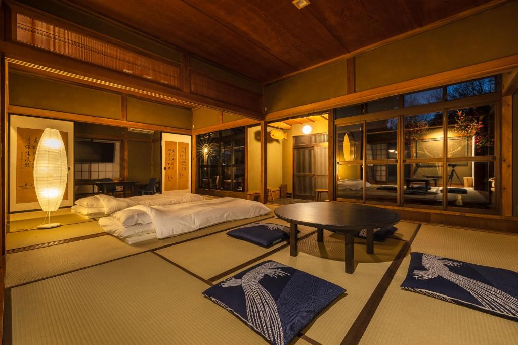 a bedroom with a bed and a table and windows at TEMPLESTAY ZENSŌ in Chiyodamachi