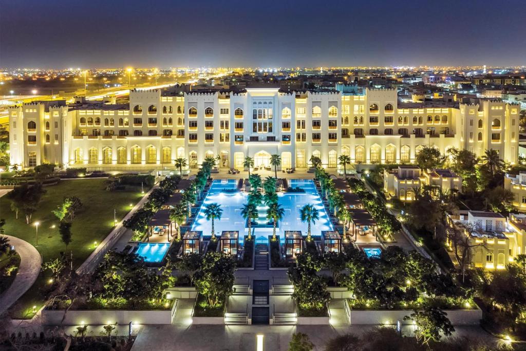 Al Messila, A Luxury Collection Resort & Spa, Doha في الدوحة: مبنى كبير مع فناء في الليل