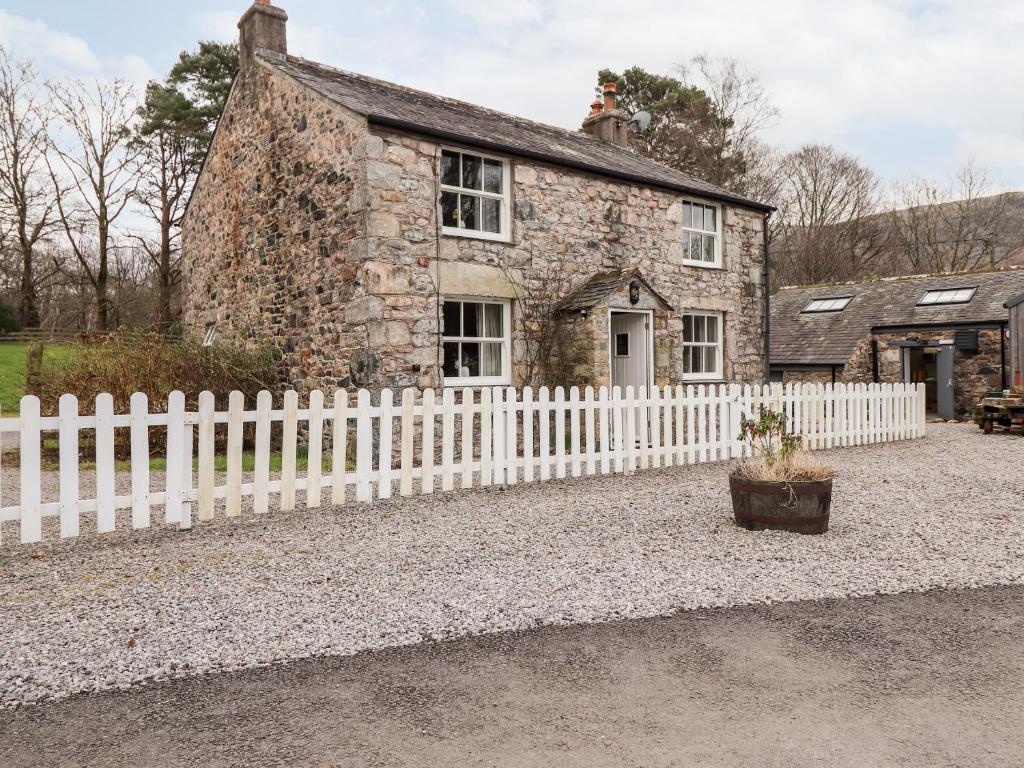 een oud stenen huis met een wit hek bij Irt Cottage in Seascale