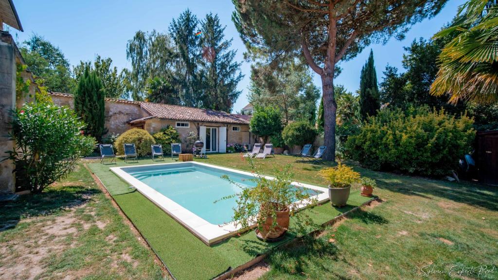 un patio trasero con piscina y una casa en I love Bergerac Cottage, en Bergerac