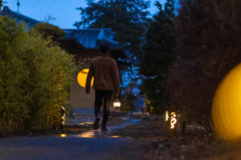 a man walking down a street with a surfboard at TEMPLESTAY ZENSŌ in Chiyodamachi